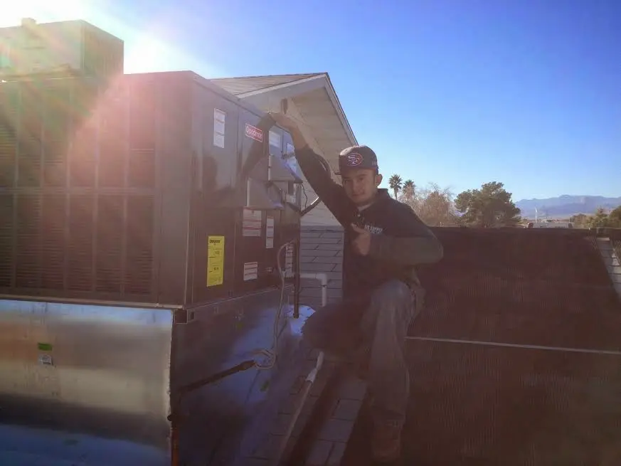 HVAC technician performing AC Tune-Up on a rooftop unit in Walpole